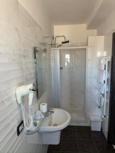 菲乌米奇诺瑞莱别墅酒店的白色的浴室设有水槽和淋浴。
