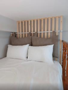普拉蒂Odyssey's Feats的一张带白色枕头和木制床头板的床