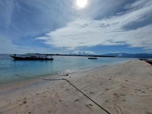 吉利特拉旺安Sahara Sands Guest House - Gili Trawangan的两艘船在水面上的海滩