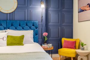 切尔滕纳姆Regency Basement Apartment的蓝色卧室,配有床和黄色椅子