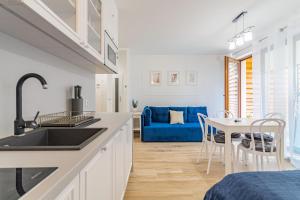 斯蒂格纳Apartamenty Mierzeja NCNK Stegna Park Standard- 500 m do plaży的厨房以及带蓝色沙发的用餐室。