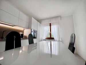 梅纳焦Casa Claude的白色的厨房配有玻璃桌和黑色椅子
