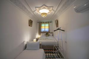 非斯Riad dar Yamna的白色卧室配有一张床和一个吊灯
