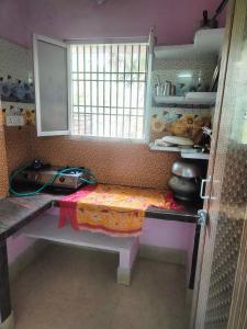 普里jharana guest house的厨房配有桌子和窗户