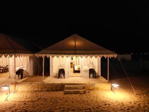 山姆Venture Desert Camp Jaisalmer的夜间带椅子的帐篷