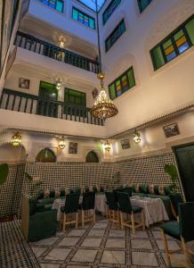 非斯Riad dar Yamna的大型客房配有桌椅和吊灯。