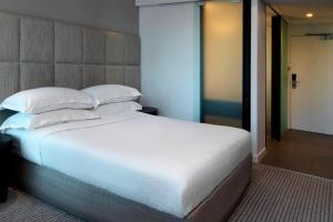 布里斯班布里斯班福朋喜来登酒店的卧室配有一张带白色床单和枕头的大床。
