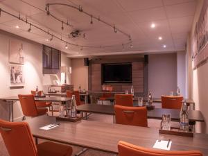 迪纳尔Royal Emeraude Dinard - MGallery的餐厅设有桌椅和平面电视。