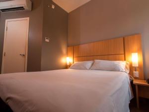普鲁登特总统城ibis Presidente Prudente Manoel Goulart的卧室配有一张带两个枕头的大白色床