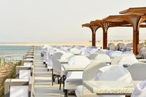 马萨阿拉姆SIRENA BEACH RESORT & SPA的海滩上一排白色的桌椅