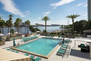 杰克逊维尔佛罗里达州杰克逊维尔河滨希尔顿逸林酒店的一个带椅子的游泳池,享有水景