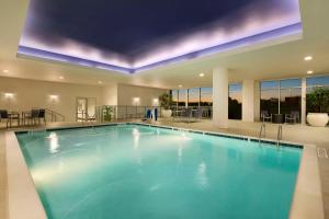 格林维尔格林维尔市中心瑞尔普雷斯希尔顿合博套房酒店的大楼内一个蓝色的大型游泳池