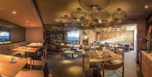 伊基托斯埃尔多拉多假日商务酒店 的餐厅设有木桌、椅子和吊灯。