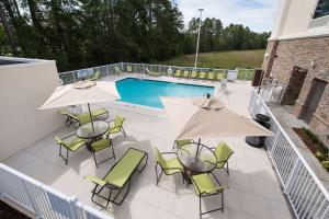 费耶特维尔Hampton Inn and Suites Fayetteville, NC的一个带椅子和遮阳伞的庭院和一个游泳池