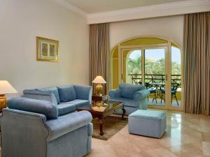 十月六日城Mövenpick Hotel Cairo - Media City的客厅配有2把蓝色椅子和桌子