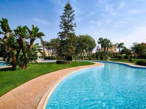 十月六日城Mövenpick Hotel Cairo - Media City的一座树木繁茂的庭院内的游泳池
