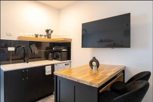 海法eve's room的一间带黑色橱柜和水槽的厨房以及一台电视。