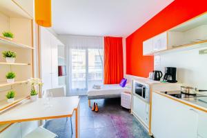 里昂Residence Montempo Lyon Cite Internationale的一个带橙色墙壁和桌子的小厨房