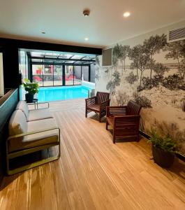 贝诺代Le Cornouaille Hotel & Spa的带沙发和椅子的客厅以及游泳池。