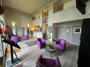 色当Hotel Inn Design Sedan的客厅配有紫色椅子和桌子