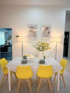 太平Homestay taiping的餐桌,配有黄色椅子和花瓶