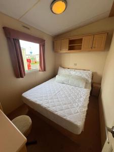 ScratbyBittern 8, Scratby - California Cliffs, Parkdean, sleeps 8, free Wi-Fi, pet friendly - 2 minutes from the beach!的一个小房间的小床,设有窗户