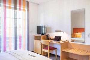 杜塞尔多夫acora Düsseldorf Living the City的酒店客房配有一张床、一张书桌和一台笔记本电脑