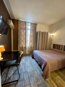 佩皮尼昂亚历山大酒店的一间卧室配有一张床、一张书桌和一个窗户。