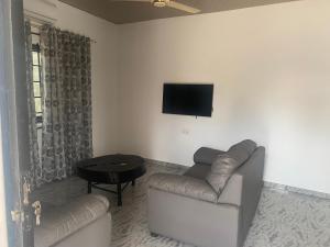 阿克拉Arm Beach Lodge的客厅配有沙发和墙上的电视