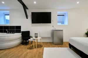 图尔昆NG SuiteHome - Lille l Tourcoing l Haute - Duplex 4 pers - Balnéo - Netflix - Wifi的一间带浴缸、一张床和电视的卧室