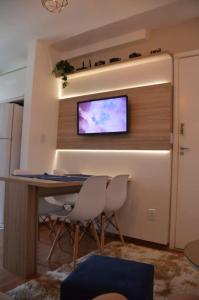 尤西德福拉Apartamento Marilândia Juiz de Fora的一间设有桌子和两把椅子的房间,墙上设有一台电视机