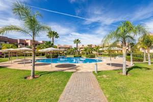 马拉喀什Golf Prestigia, grande piscine, jardins的棕榈树公园内的游泳池