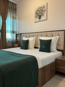 普里什蒂纳Hotel Uniluxury的一间卧室配有一张带绿色和白色枕头的大床