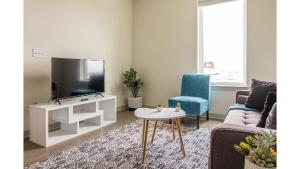 路易斯威尔Stunning Nulu 1BR CozySuites Unit 03的客厅配有电视、沙发和桌子