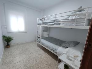 卡马斯Precioso apartamento en Sevilla.的白色卧室配有双层床和植物