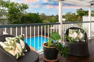 布里斯班The Indooroopilly Queenslander - 4 Bedroom Family Home - Private Pool - Wifi - Netflix的一个带两把椅子的阳台和一个游泳池