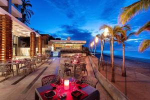 卡波圣卢卡斯Residential Retreat 3 Bedroom Suite Ocean Front Garza Blanca Los Cabos Resort & Spa的海滩上的餐厅,设有桌子和棕榈树
