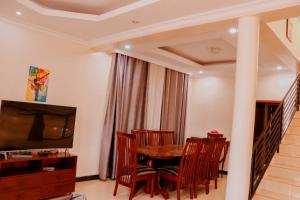 基加利Kigali Homes Villa的一间带桌椅和电视的用餐室