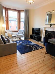 格拉斯哥Beautiful & spacious 2 bed apt in Glasgow West End的客厅配有沙发、椅子和壁炉