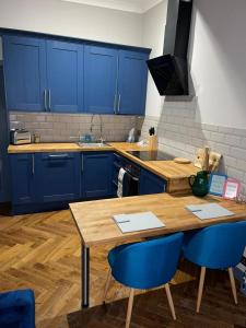 格拉斯哥Stunning 1 bed Apt in West End的厨房配有蓝色橱柜和木桌及椅子