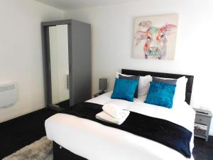 汉密尔顿Newly refurbished 2 bedroom apartment close to station and local amenities的卧室配有带蓝色枕头的大型白色床