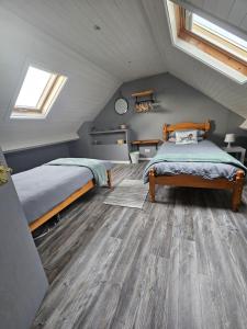 奥马Kingarrow Cottage的阁楼卧室配有两张床,铺有木地板