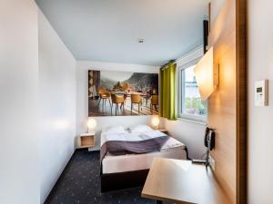 莱茵河畔威尔B&B Hotel Weil am Rhein/Basel的酒店客房配有一张床铺和一张桌子。