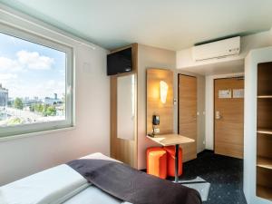莱茵河畔威尔B&B Hotel Weil am Rhein/Basel的一间卧室配有一张床、一张书桌和一个窗户。