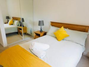 格拉斯哥Brand new gorgeous 2 bed Apt in Finnieston的一间卧室配有一张白色的床、黄色枕头和镜子