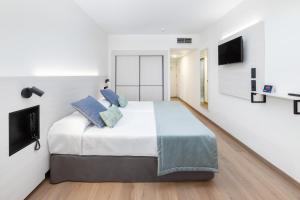 美洲海滩Alexandre Hotel Troya的白色卧室配有一张带蓝色枕头的大床