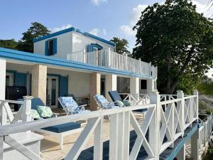 FrederikstedNorth Star Villa Oceanfront Family-Retreat With Pool的甲板上摆放着蓝色和白色椅子的房子