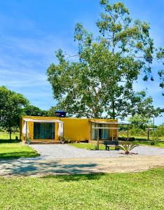 南圣弗朗西斯科Container Suítes Recanto Monte Trigo的公园里带长凳的黄色房子