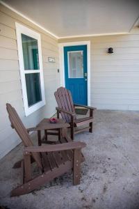 沃思堡Stockyards Cowtown Outpost-Less than 4 minutes to StockYards-Sleeps 8的两把椅子坐在房子外面,有一扇蓝色的门