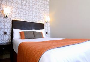 奥本天鸽座酒店的一间卧室配有一张带橙色毯子的大床
